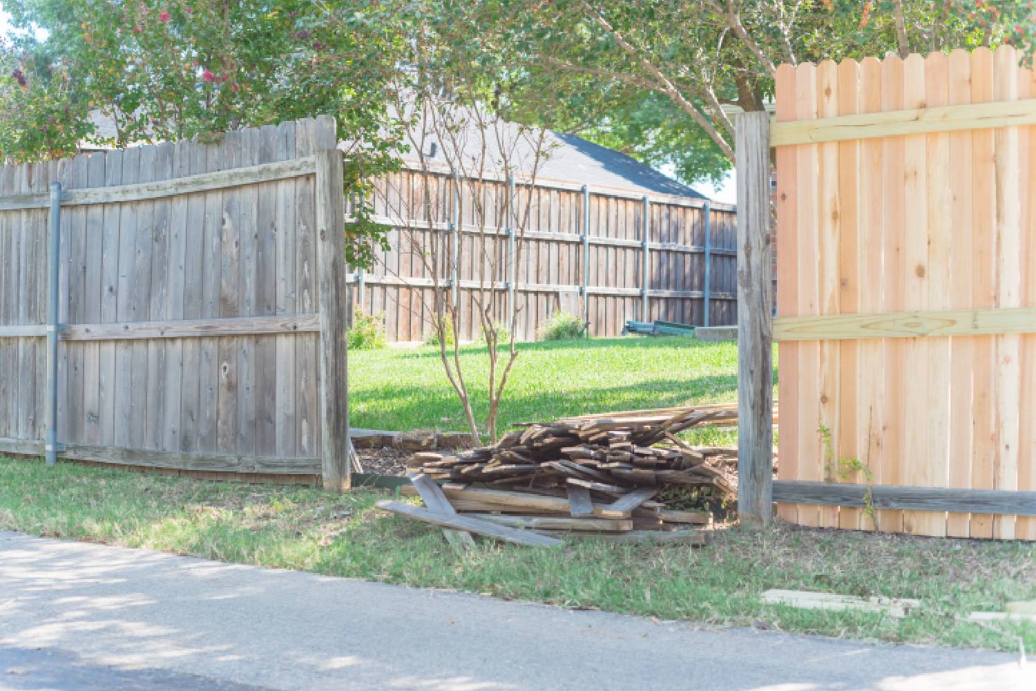 Man in protective gloves is painting wooden fence in bright summer day.